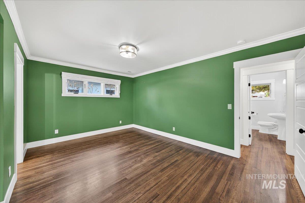 Unfurnished bedroom with crown molding and dark wood-style floors