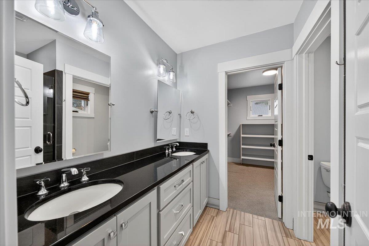 Full bath with double vanity, wood finish floors, and a walk in closet
