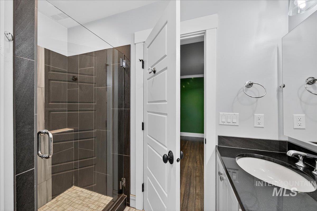 Bathroom featuring a stall shower, vanity, and dark wood finished floors