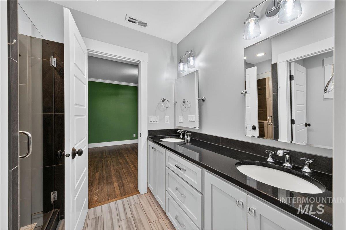 Full bath featuring light wood-type flooring, double vanity, and a stall shower