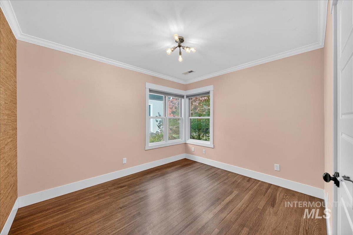 Spare room featuring crown molding and dark wood finished floors