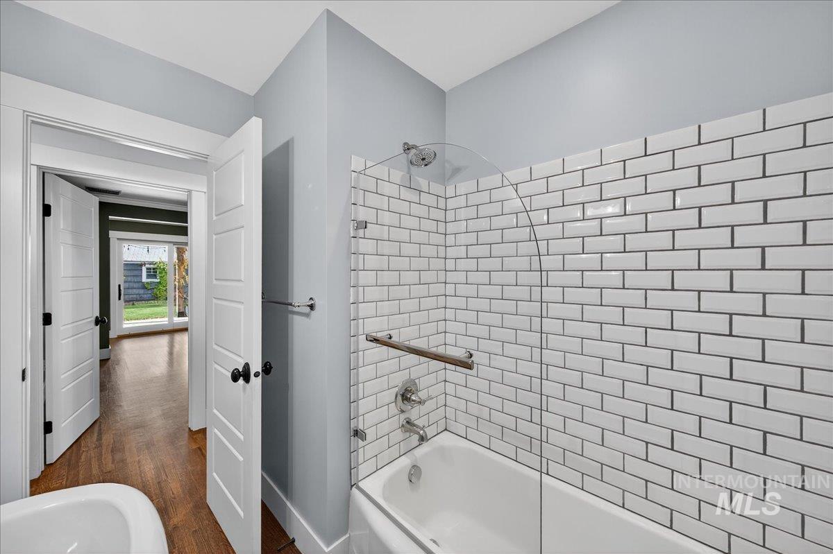 Full bath with shower / tub combination and dark wood-style floors