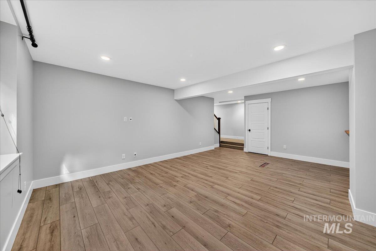 Finished below grade area with recessed lighting, light wood-style flooring, and stairway