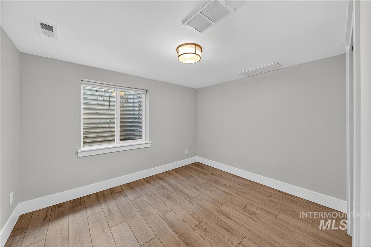 Empty room featuring baseboards and light wood-style flooring