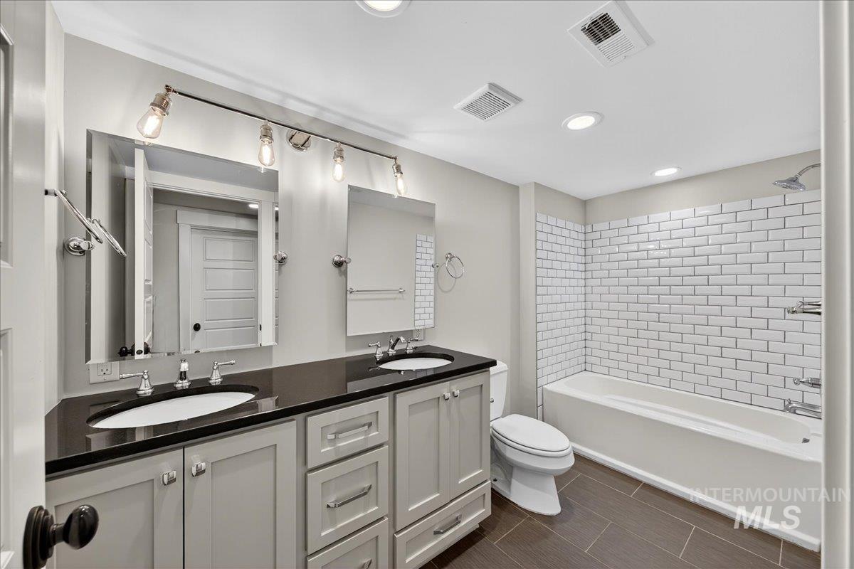 Full bathroom with recessed lighting, double vanity, and bathing tub / shower combination