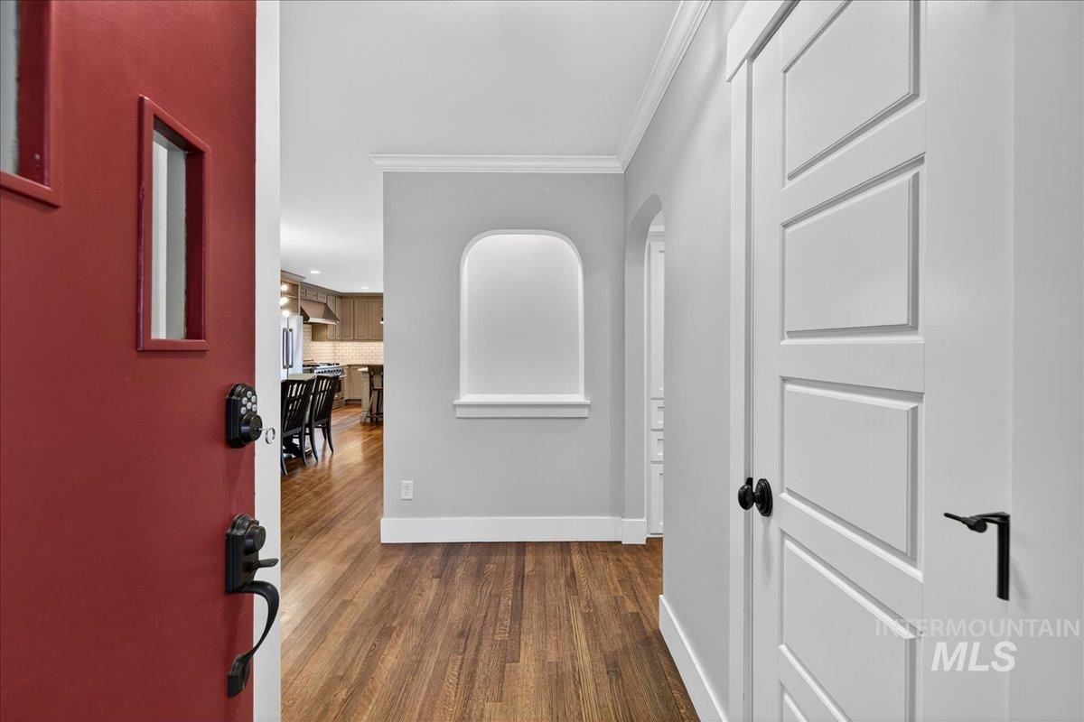 Hallway featuring ornamental molding, dark wood-style flooring, and arched walkways