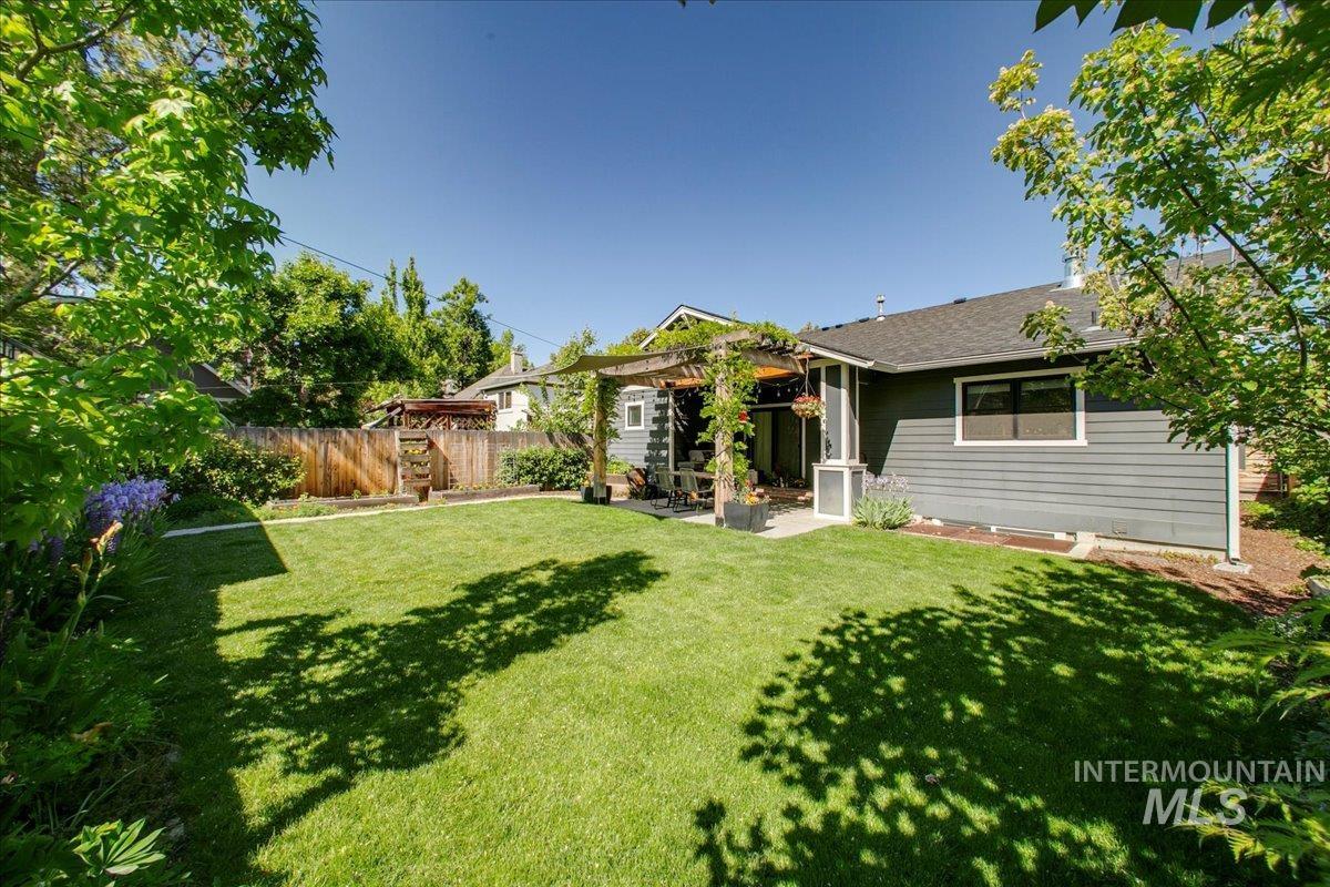 View of front of home with a patio, a fenced backyard, a pergola, and roof with shingles