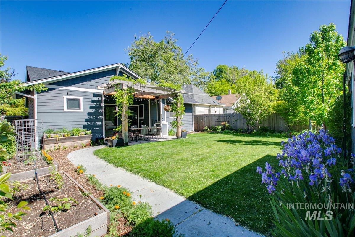 Rear view of house featuring a garden, a patio area, a fenced backyard, and a pergola