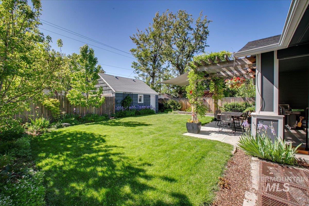 Fenced backyard featuring a pergola, a patio area, and an outbuilding