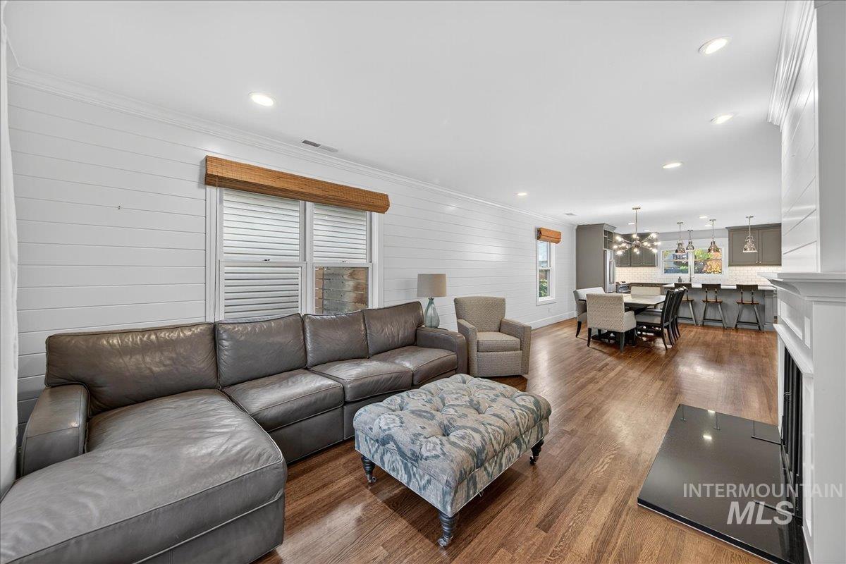 Living room with dark wood-style floors, recessed lighting, ornamental molding, a fireplace, and a chandelier