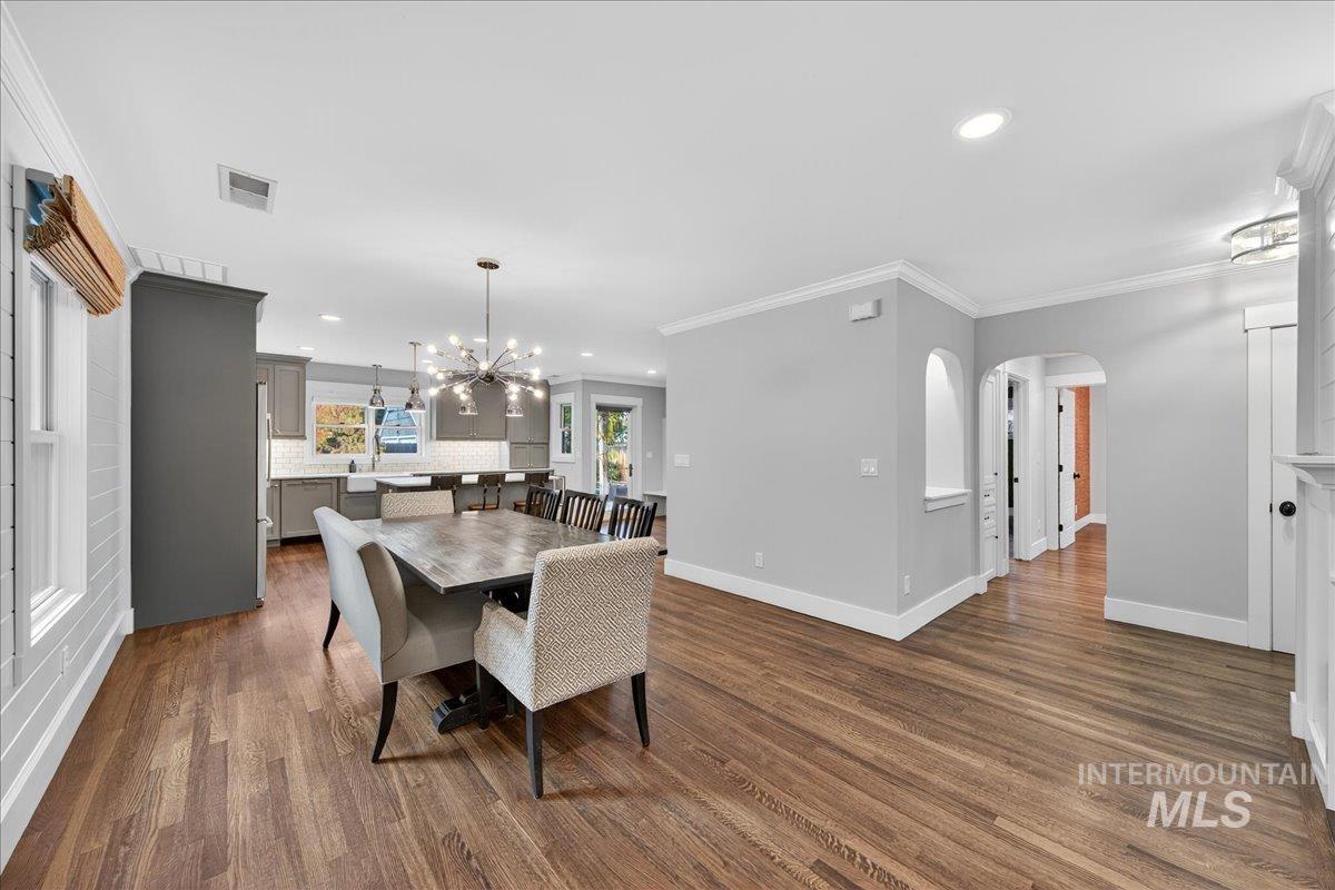 Dining area featuring ornamental molding, arched walkways, recessed lighting, dark wood-style flooring, and a chandelier