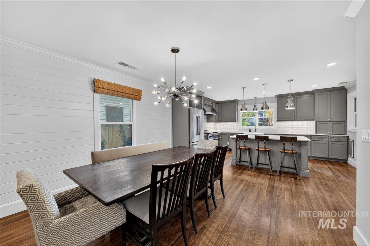 Dining room with crown molding, a chandelier, dark wood-type flooring, and recessed lighting