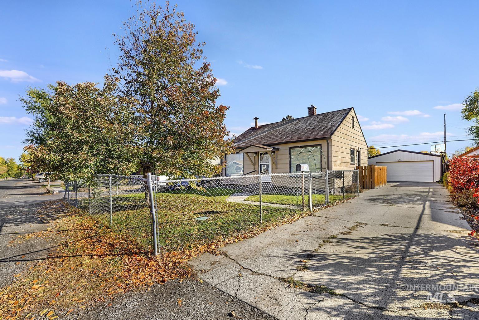 Bungalow featuring a fenced front yard, a detached garage, an outdoor structure, and a chimney