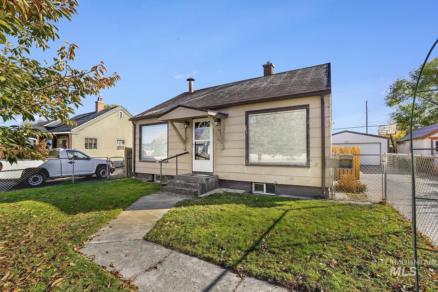 Bungalow-style home with a chimney, a gate, a garage, an outbuilding, and roof with shingles