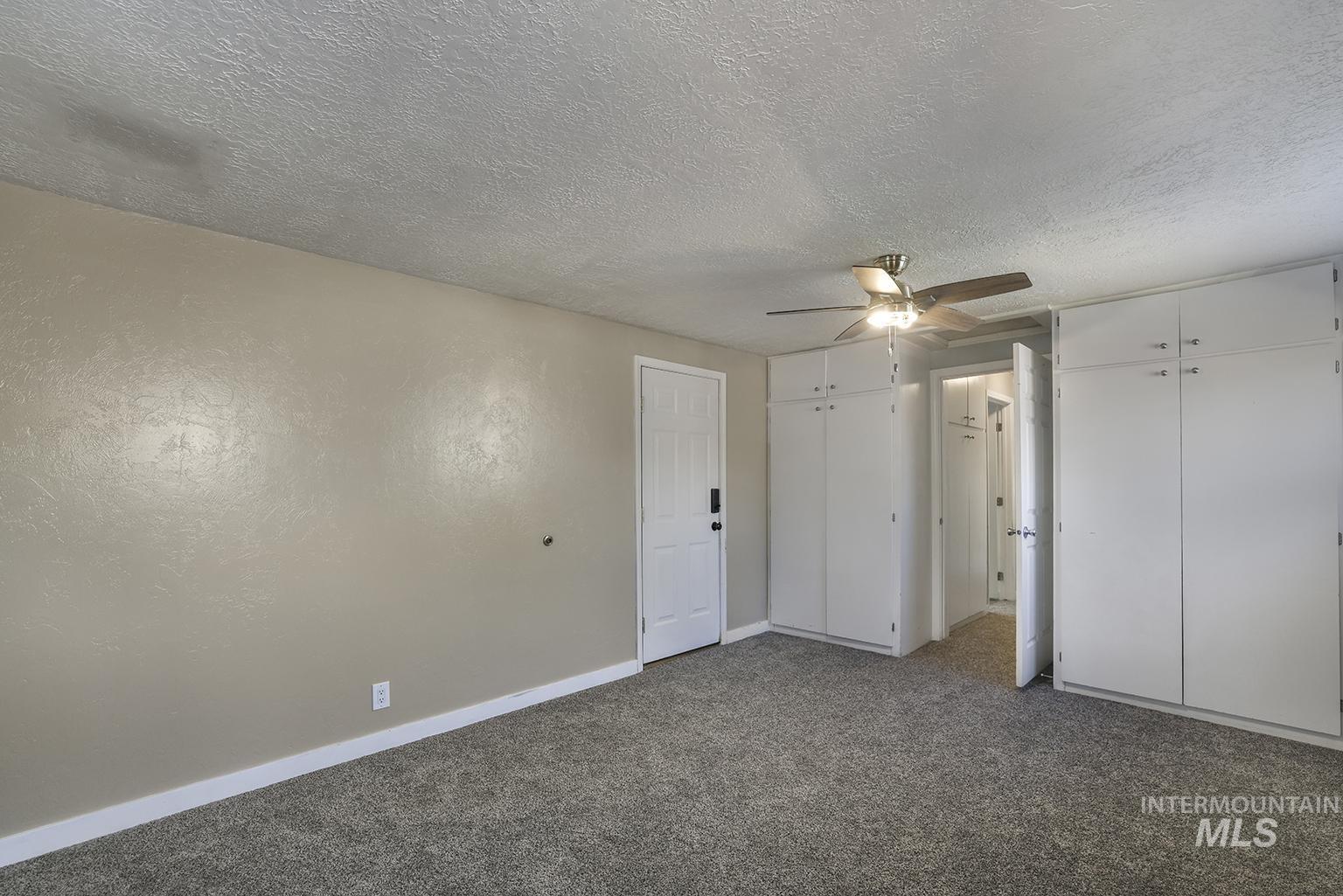 Unfurnished bedroom featuring carpet floors, a textured ceiling, and ceiling fan