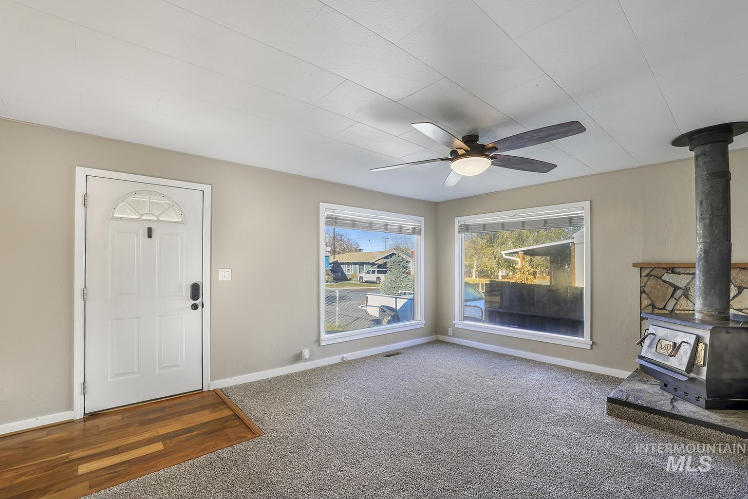 Foyer entrance featuring a wood stove, carpet flooring, and a ceiling fan