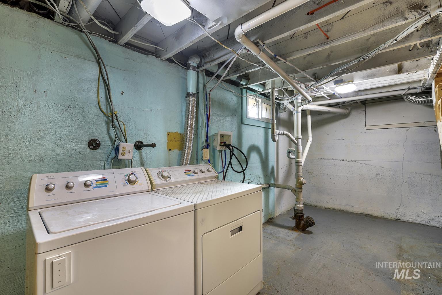 Washroom with concrete flooring and washing machine and clothes dryer