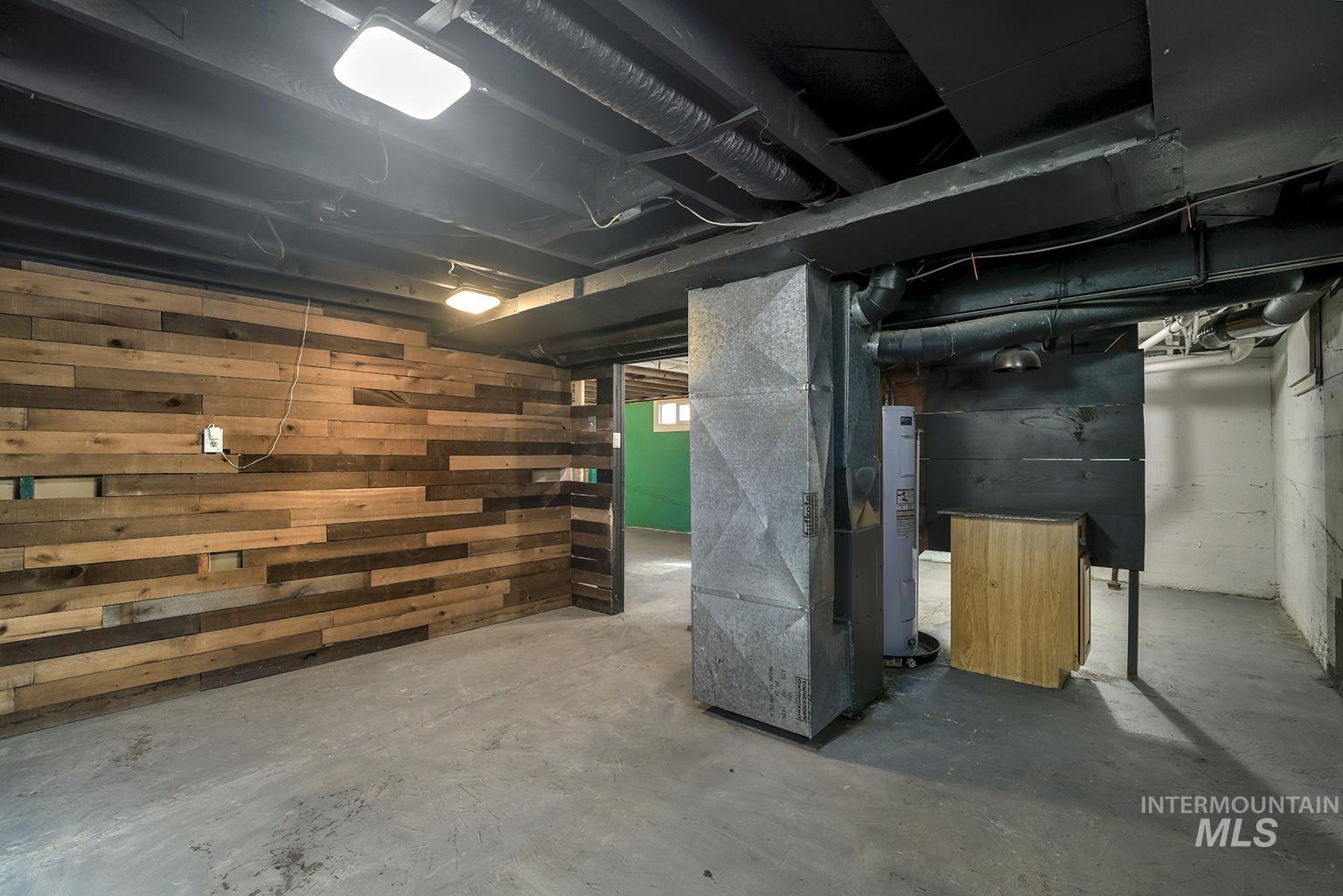 Unfinished basement with heating unit, water heater, and wooden walls