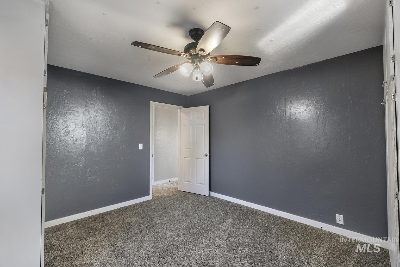 Unfurnished room featuring carpet floors, ceiling fan, and a textured wall