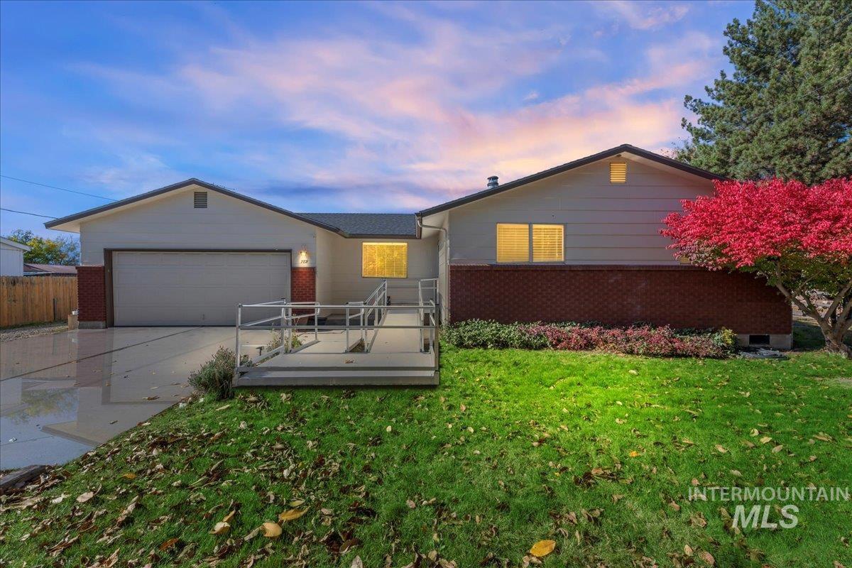 Ranch-style house featuring driveway, a deck, an attached garage, and brick siding