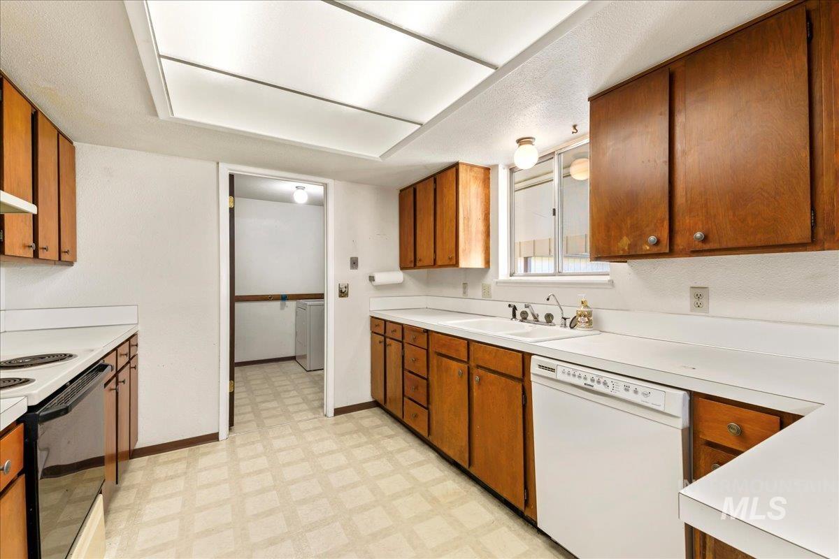 Kitchen featuring light floors, white appliances, and brown cabinets