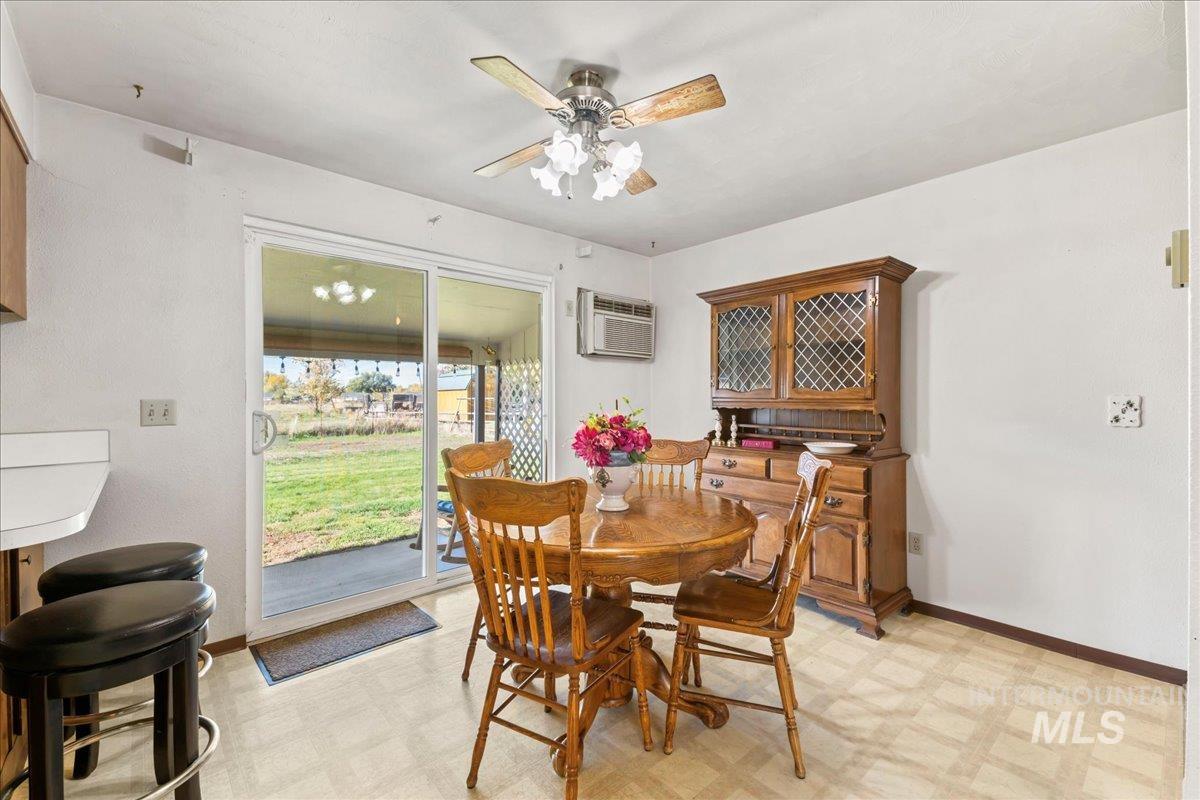 Dining space featuring light flooring, a ceiling fan, and a wall mounted AC