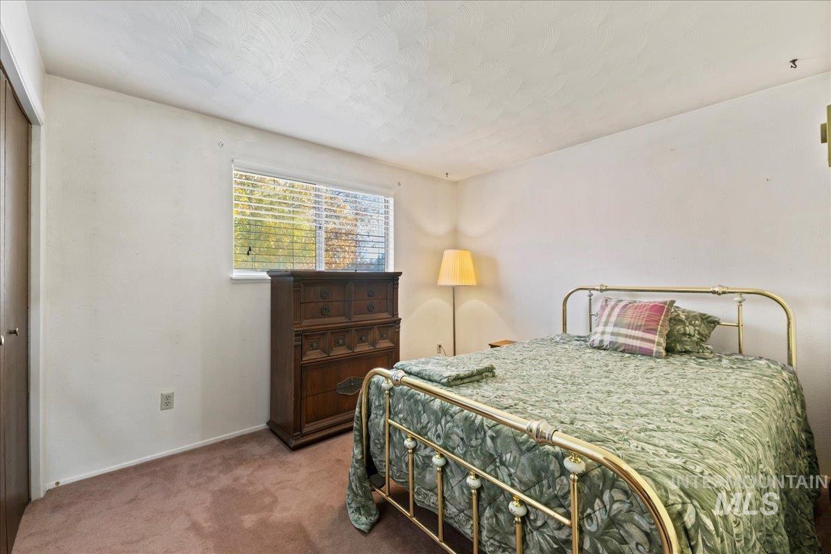 Carpeted bedroom with a textured ceiling and a closet