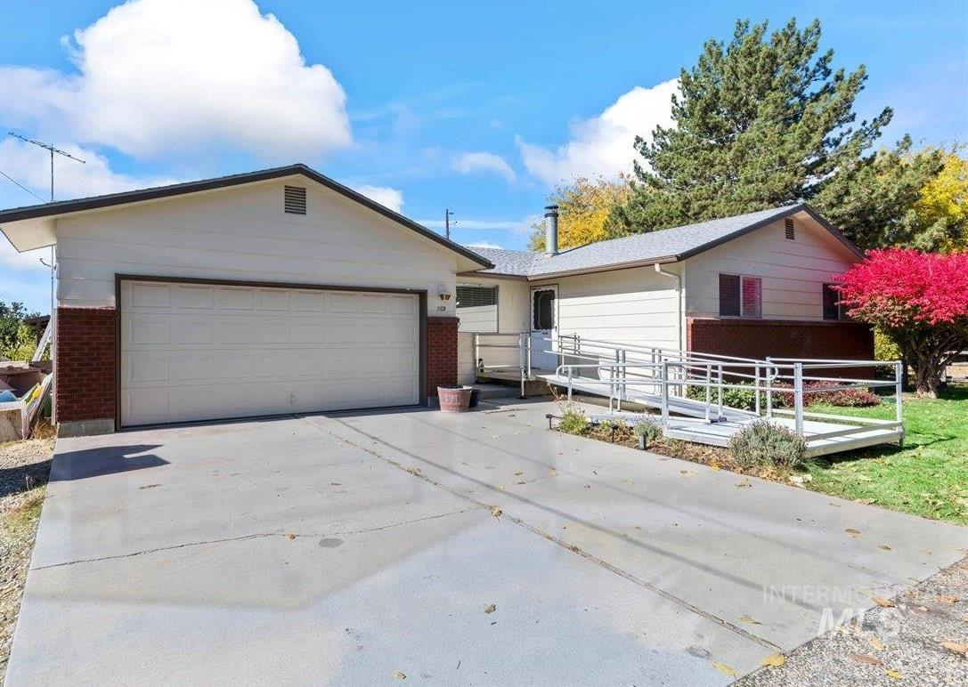 Ranch-style house featuring driveway, brick siding, and an attached garage
