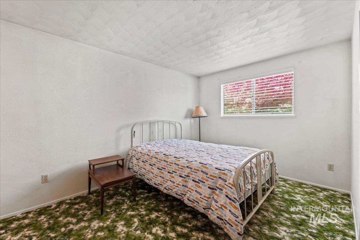 Bedroom with a textured wall, carpet flooring, and a textured ceiling
