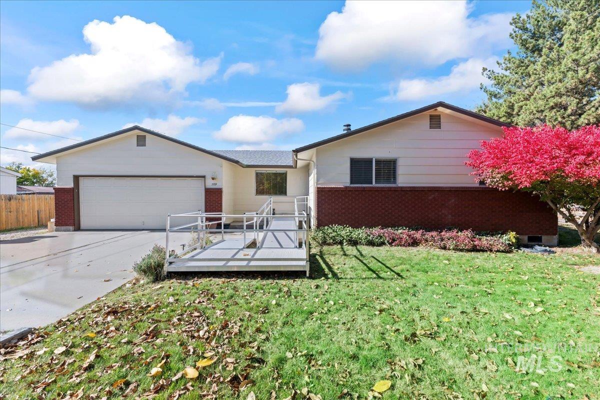 Ranch-style home featuring concrete driveway, a garage, a wooden deck, and brick siding
