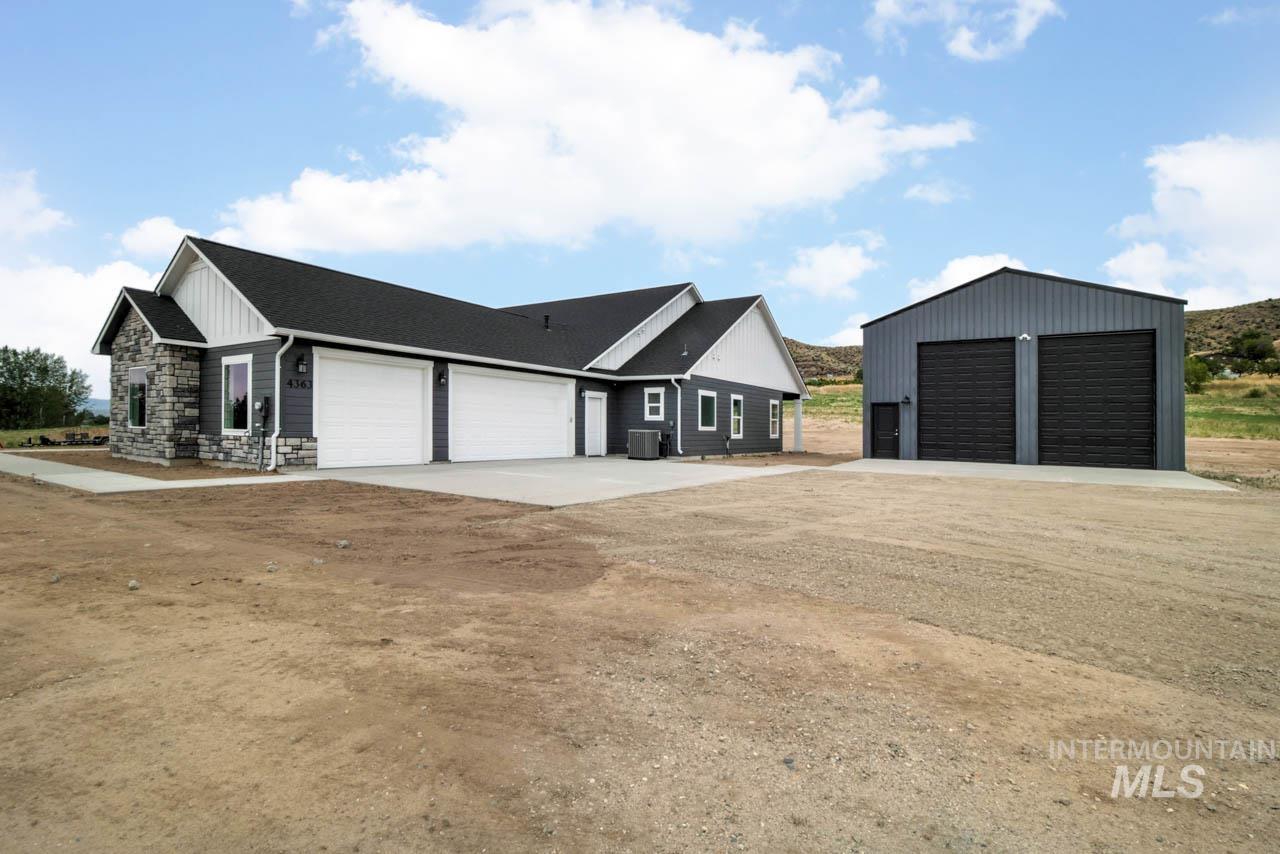 View of side of home featuring stone siding, a detached garage, and a shingled roof