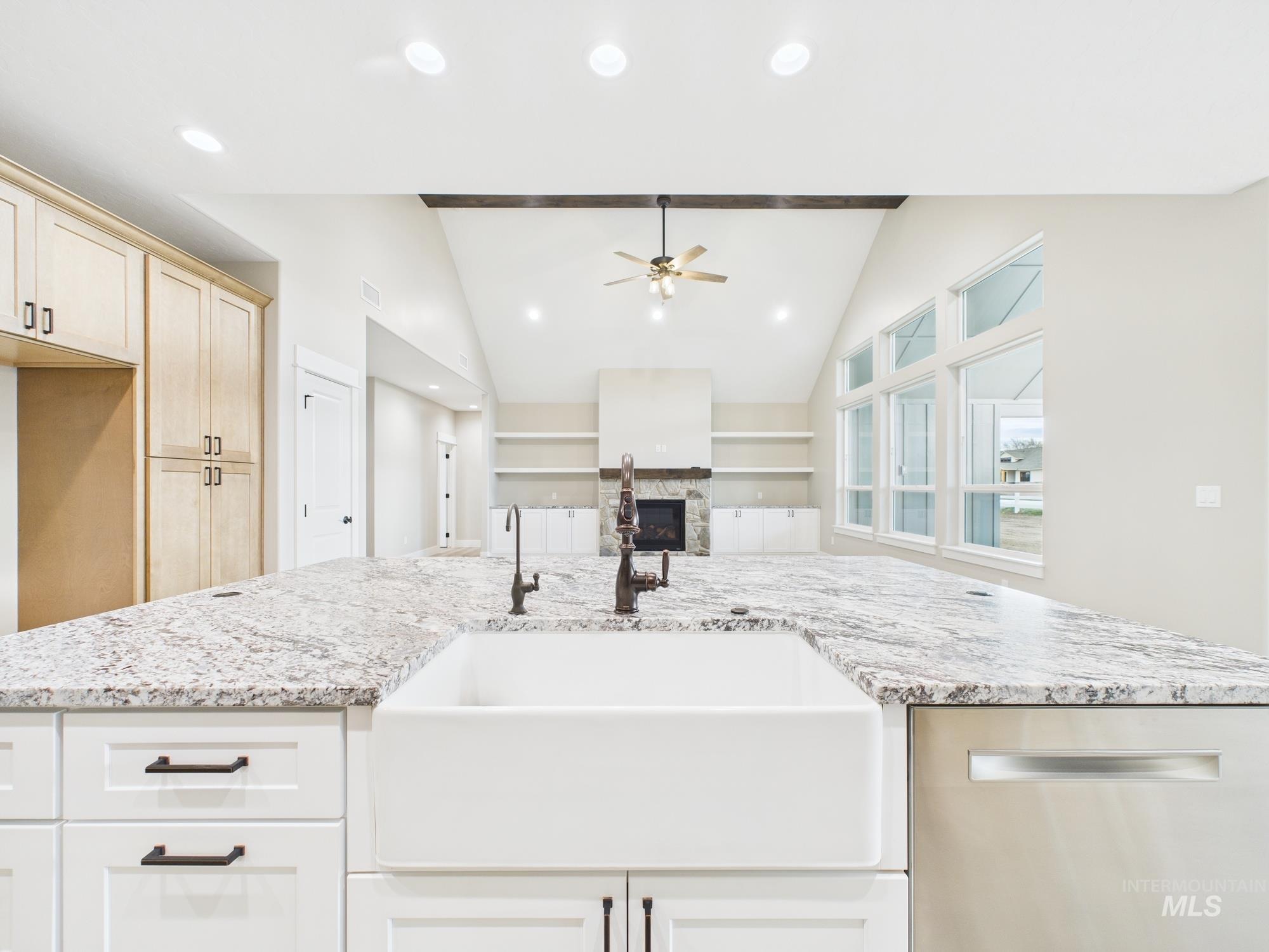 Kitchen featuring stainless steel dishwasher, a stone fireplace, vaulted ceiling, recessed lighting, and a ceiling fan