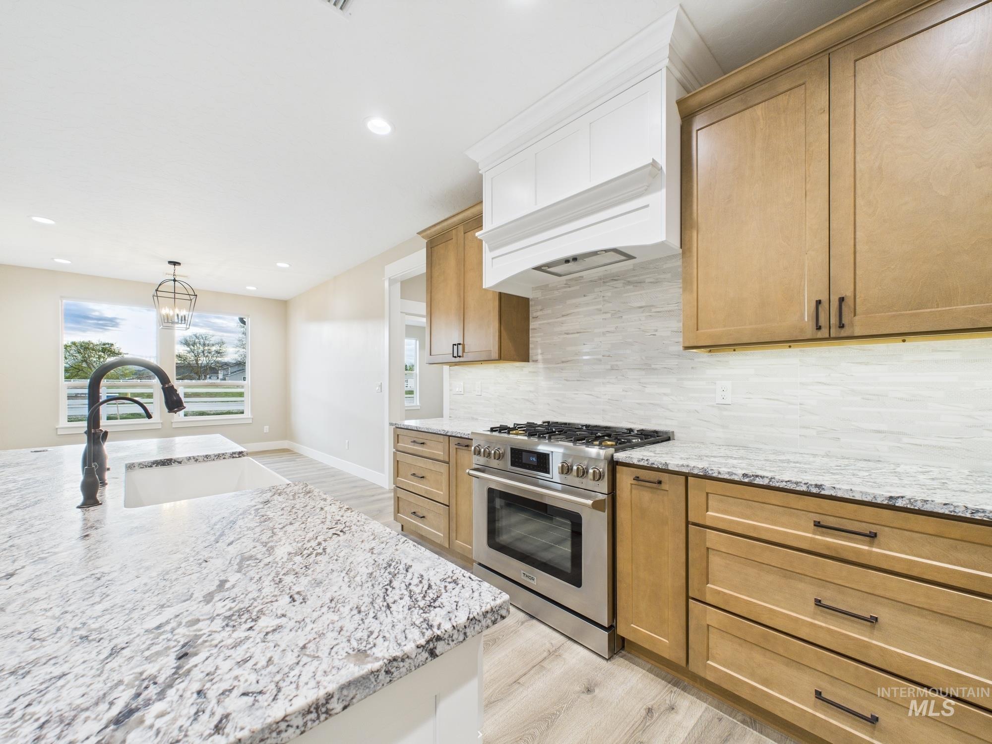 Kitchen featuring stainless steel range with gas stovetop, light wood-style flooring, light stone counters, and recessed lighting