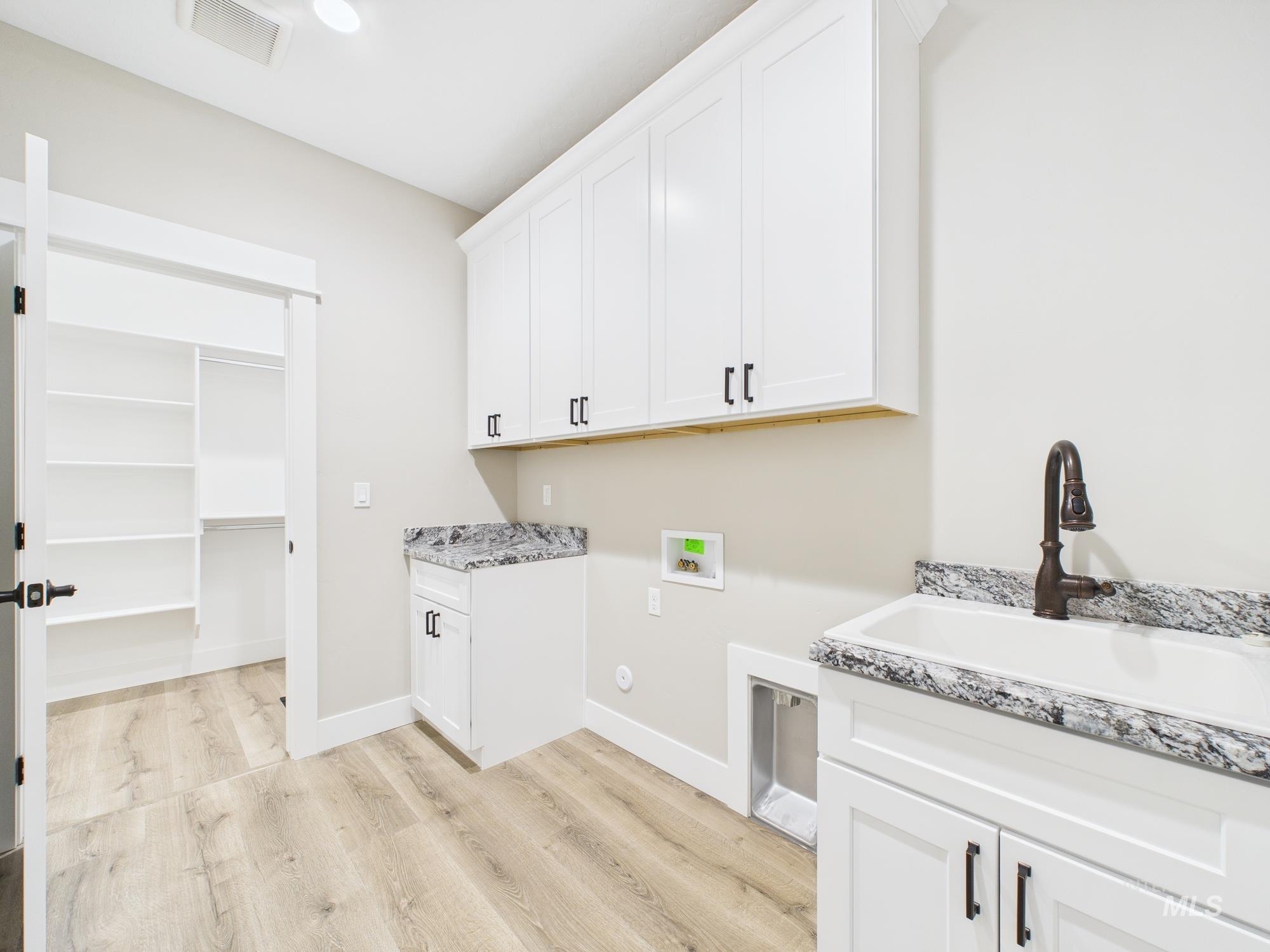 Washroom featuring cabinet space, hookup for a washing machine, and light wood-style floors