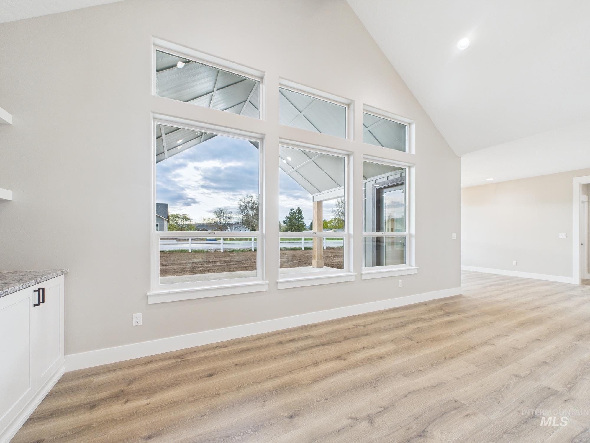 Unfurnished living room featuring light wood-type flooring, high vaulted ceiling, and recessed lighting