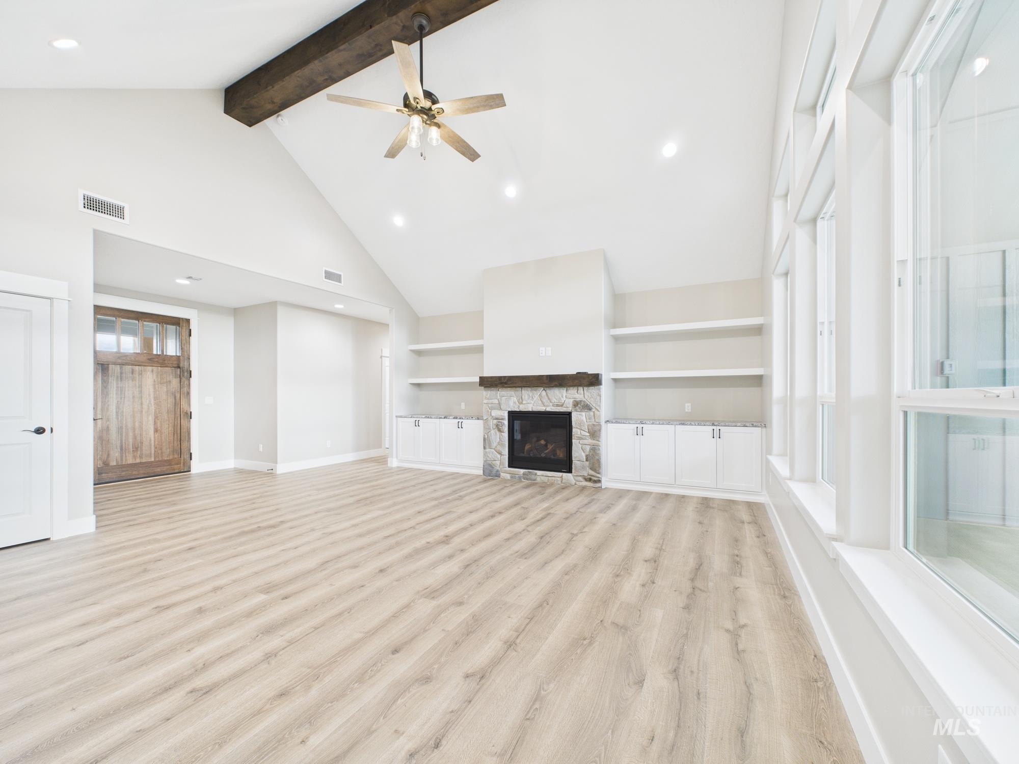 Unfurnished living room with built in features, light wood-style floors, beam ceiling, a fireplace, and recessed lighting