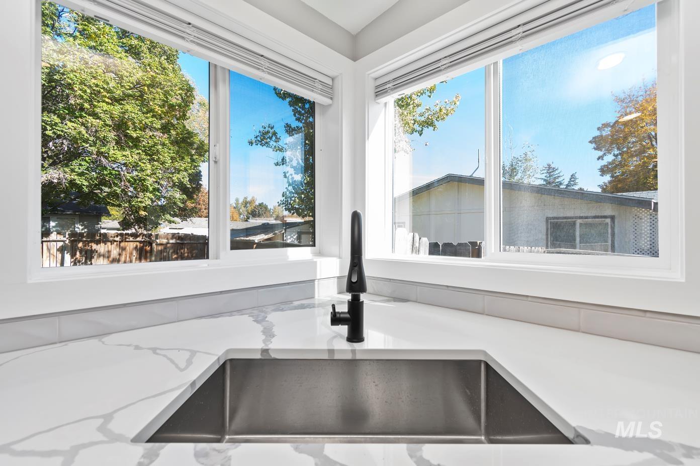 Kitchen view of light stone counters and a sink