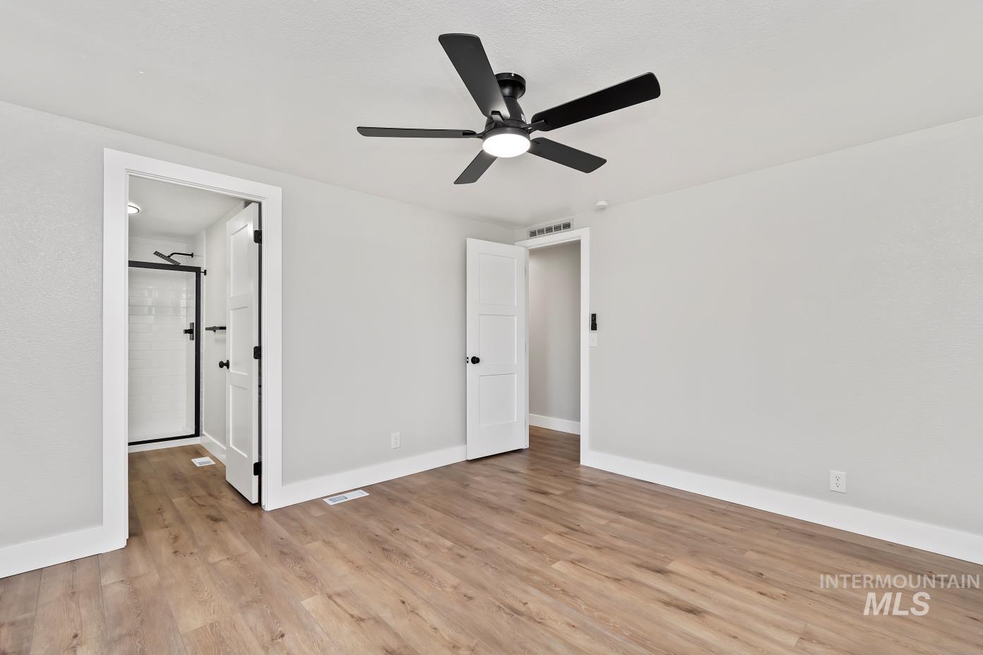 Unfurnished bedroom with light wood-style floors, ceiling fan, and connected bathroom