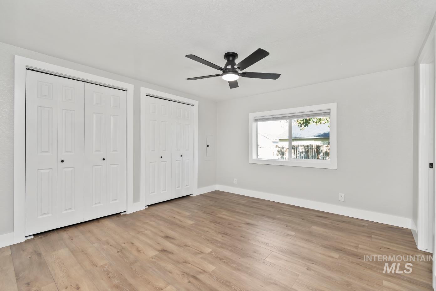 Unfurnished bedroom with two closets, light wood-style floors, and a ceiling fan