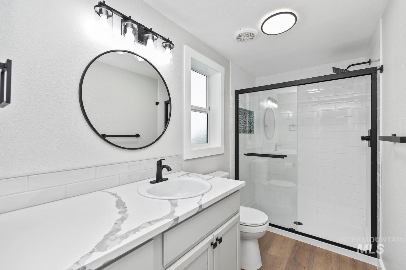 Bathroom with dark wood-style flooring, vanity, and a stall shower