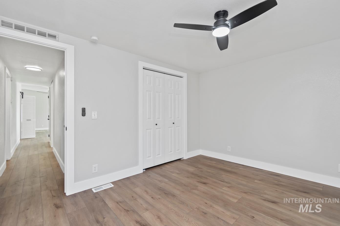 Unfurnished bedroom with light wood-type flooring, ceiling fan, and a closet