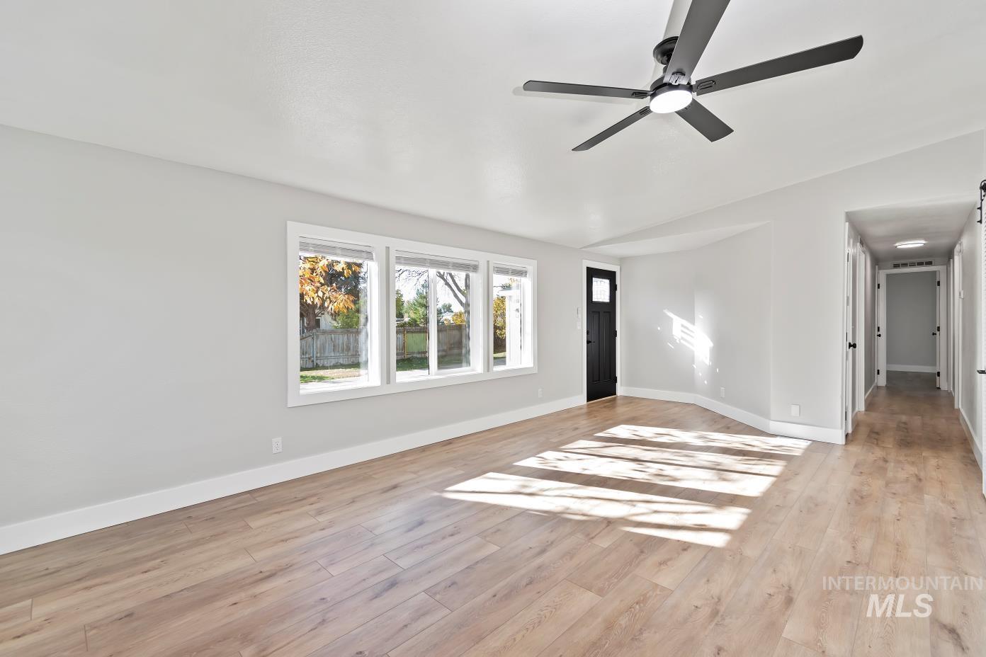 Unfurnished living room featuring light wood-style flooring and ceiling fan