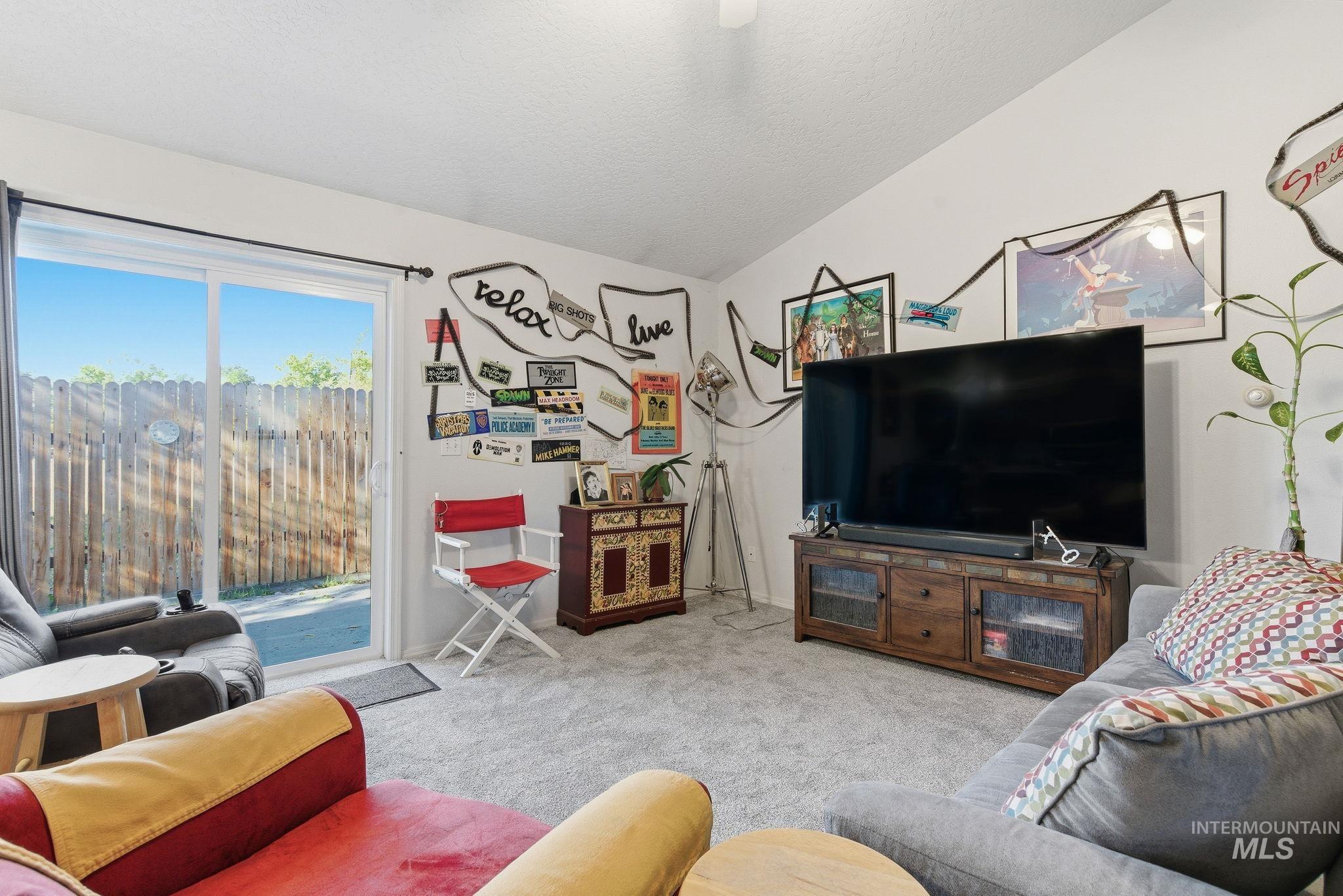 Carpeted living area featuring lofted ceiling and baseboards