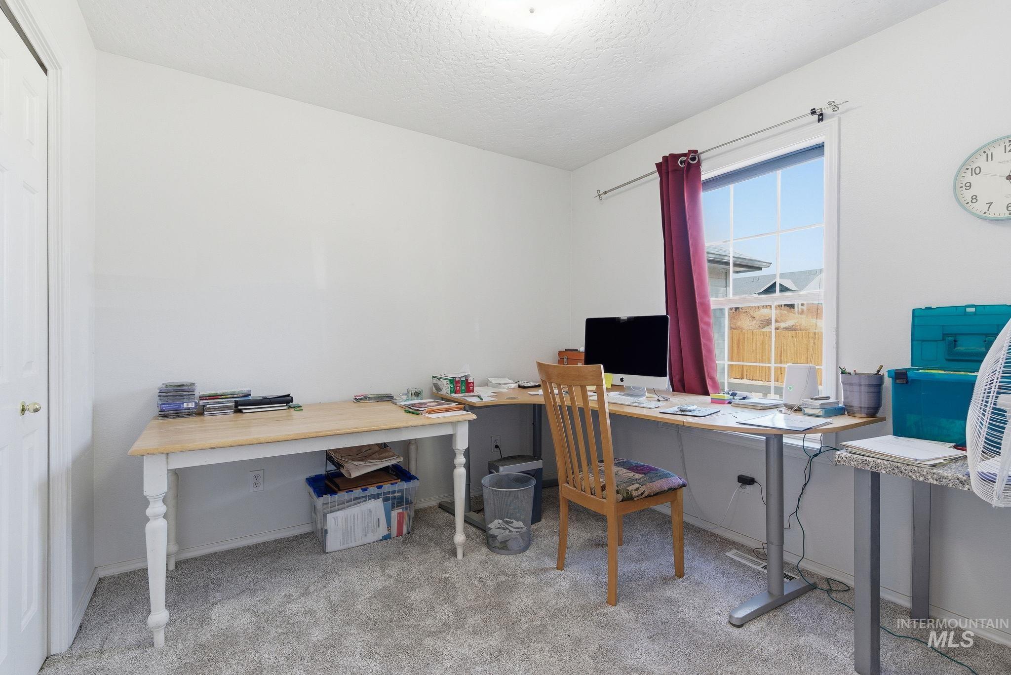 Home office featuring light carpet and a textured ceiling