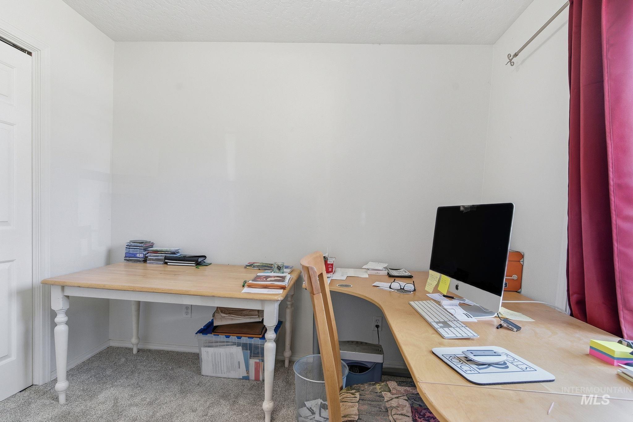 Office space featuring light colored carpet and a textured ceiling