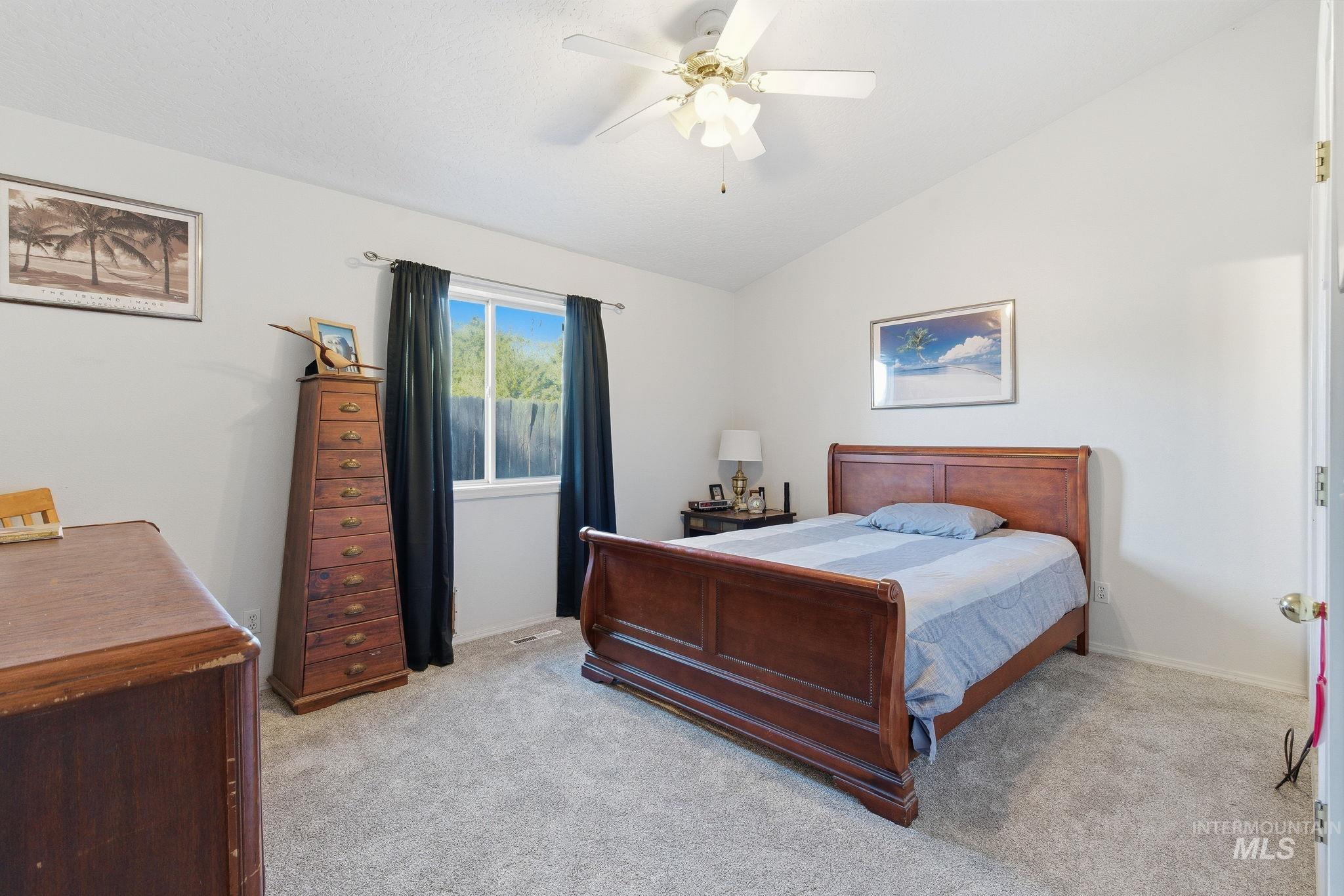 Bedroom featuring light colored carpet, lofted ceiling, and ceiling fan