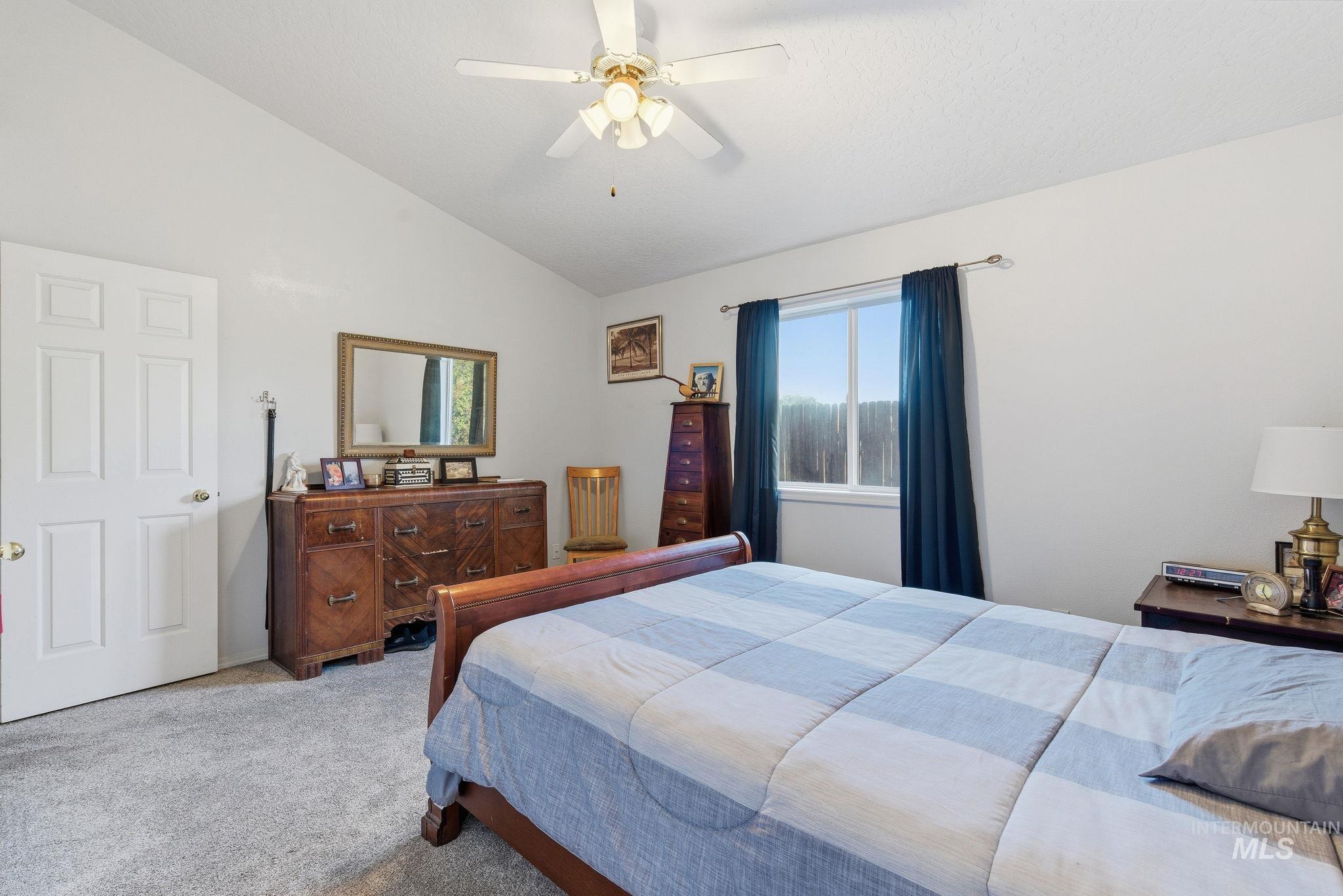 Carpeted bedroom with vaulted ceiling and a ceiling fan