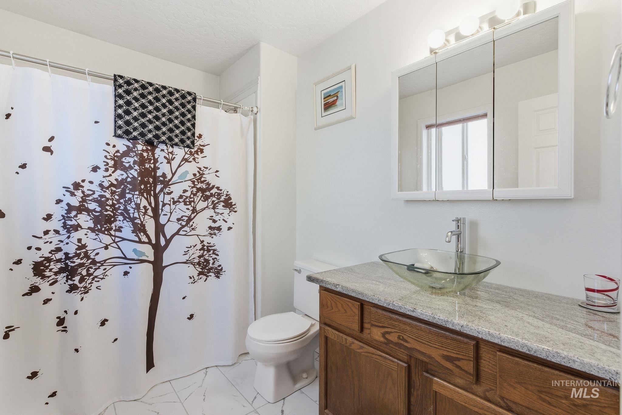 Full bathroom featuring a shower with curtain, vanity, and a textured ceiling