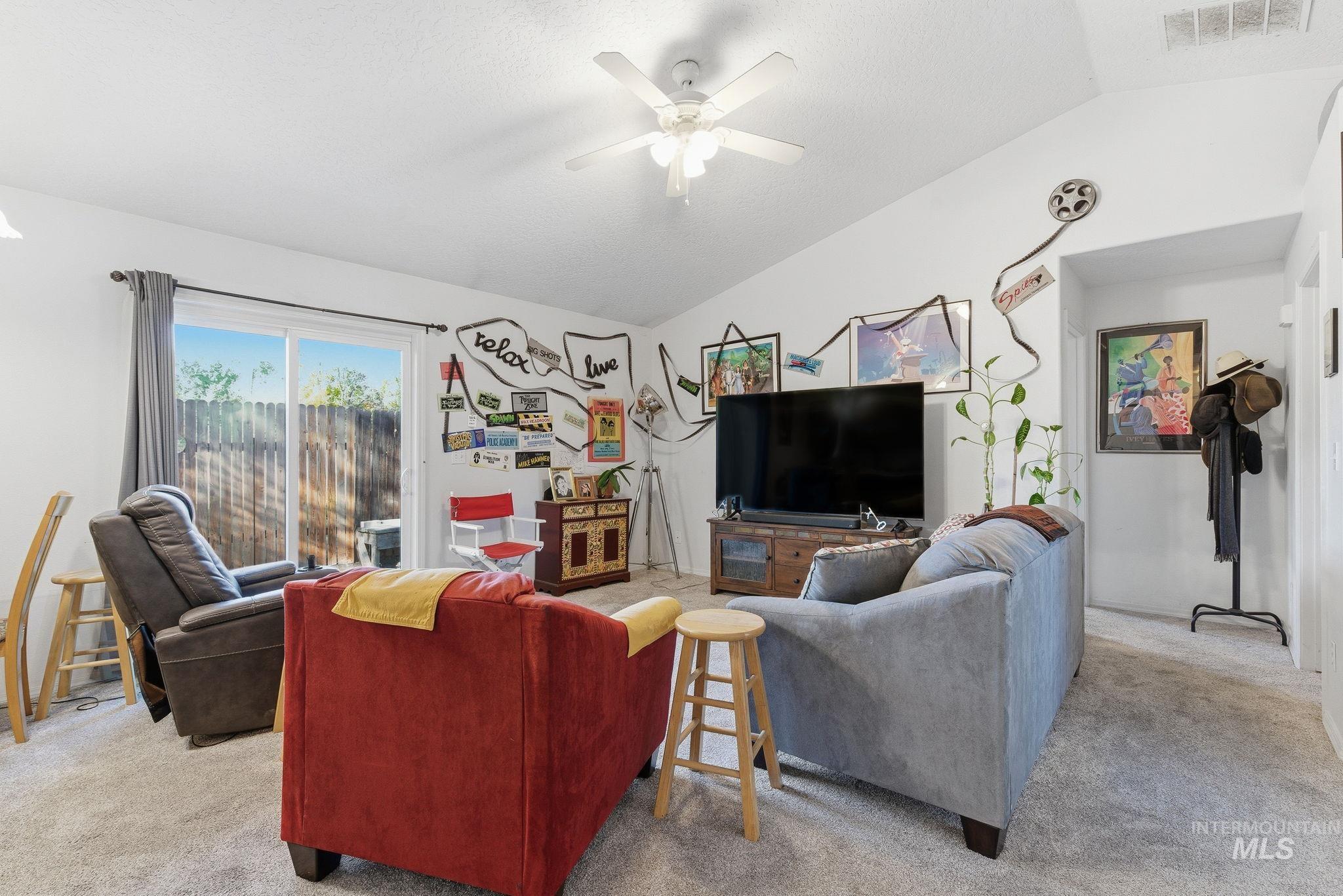Carpeted living room with lofted ceiling and ceiling fan