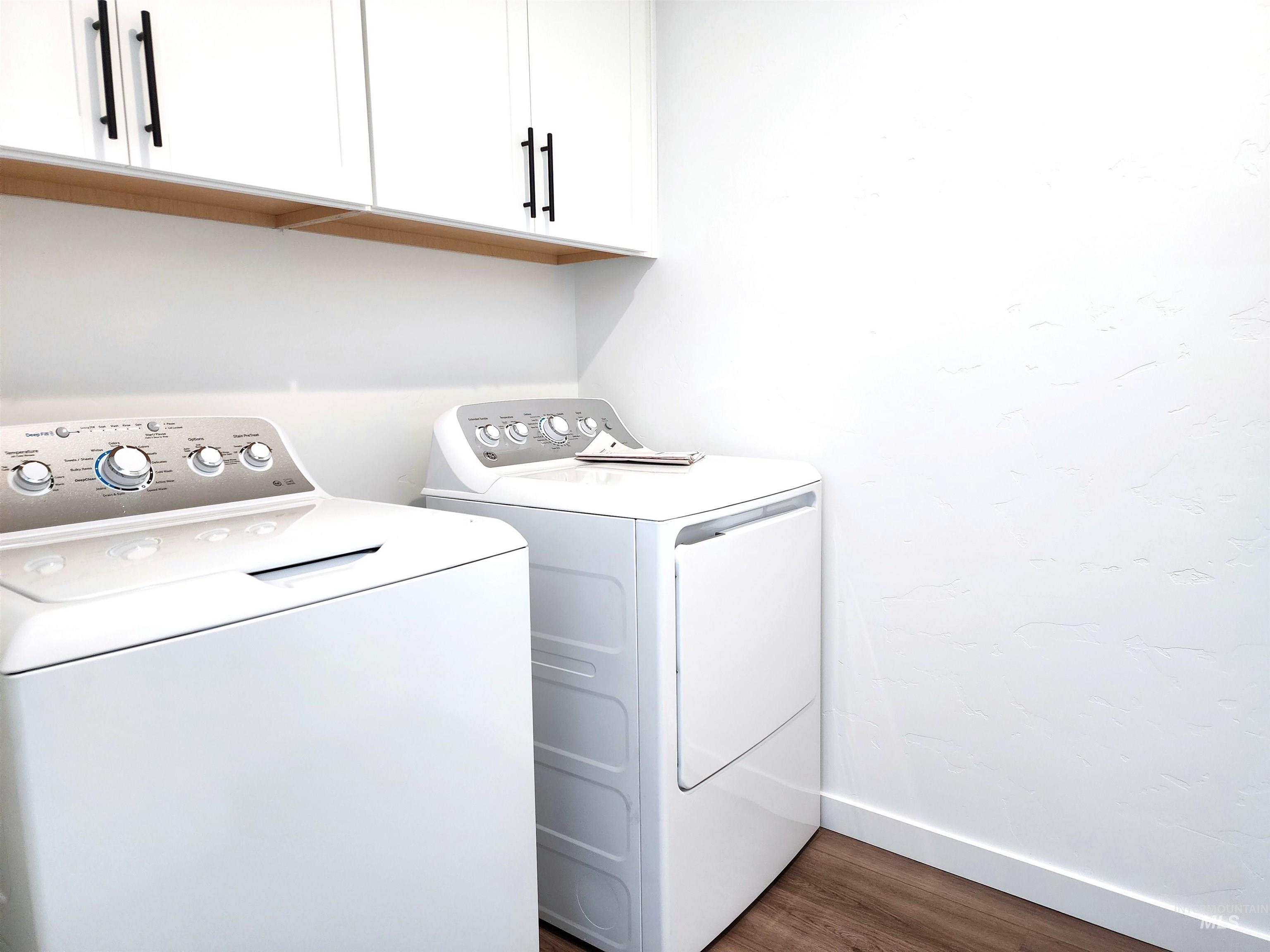 Laundry room with dark wood-style flooring, washer and dryer, and cabinet space